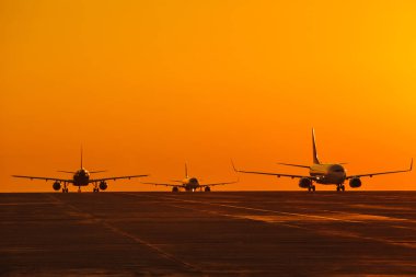 Gün batımında renkli gökyüzüne iniş yapan uçaklar. Yolcu uçağıyla seyahat edin. Ticari uçak. Özel jet. Tahliye.