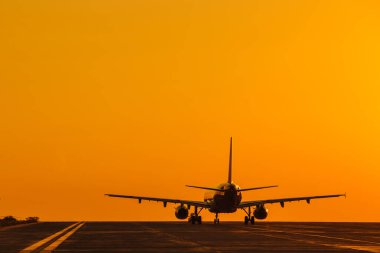 Hava uçağının silueti gün batımında iniyor. Arka planda güzel bir kızıl gökyüzü var. Ticari uçak. Özel jet. Tahliye.