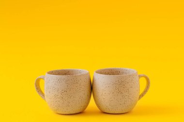 Sarı zemin üzerinde iki boş seramik bardak, boşluğu kopyala.