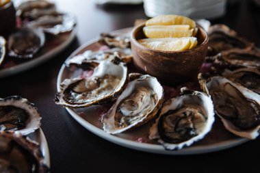 Tabakta taze istiridye, istiridyelerle servis edilen masa, restoranda limon. Gurme yemekleri..