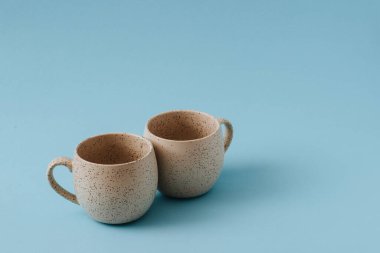 Mavi arkaplanda iki porselen boş bardak, boşluğu kopyala