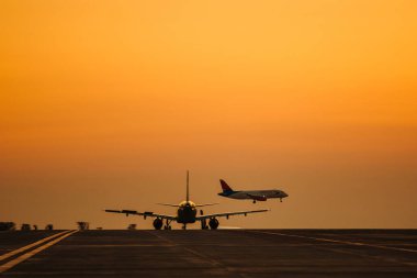 Havaalanından kalkan yolcu uçağı, güneş ışınlarıyla dolu pitoresk bir akşam gökyüzünün arka planına doğru havalanıyor..