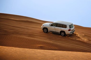 Dubai, Birleşik Arap Emirlikleri - 01 Temmuz 2021: Kum tepelerinin üzerindeki Arap Çölü 'nde araba yolculuğu. Çölde sıcak bir gün.