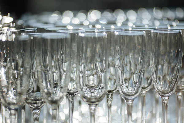 Group of empty and transparent champagne glasses in a restaurant. Clean glasses on a table prepared by the bartender for champagne. Catering for the event preparation, empty glasses for drink.