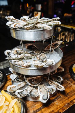 Koyu ahşap arka planda limonlu, beyaz bir tabakta istiridye, deniz ürünü, yumuşakça, lüks..