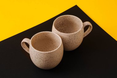 Siyah ve sarı arkaplanda iki porselen boş bardak, boşluğu kopyala.