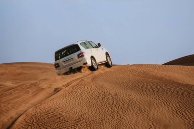 Dubai, Birleşik Arap Emirlikleri - 01 Temmuz 2021: Kum çölünde yarış. Yarış yarışı çölü. Araba toz bulutlarıyla yoldan çıkıyor. Yabanda engellerle yarışan off road aracı
