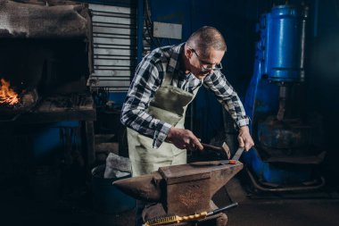 Demirci demirci demircideki kızgın metali elle dövüyor. Sıkı çalışma. Enerji ve güç. Çalışma anlayışı, geçmişe dönük meslekler