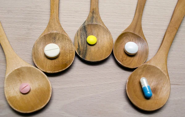 Pills and capsule with wooden spoon on wood background — Stock Photo, Image