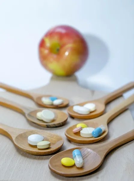 Pills and capsule with wooden spoon on wood background — Stock Photo, Image