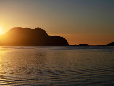 Norveç kıyısında parlayan turuncu gün batımı