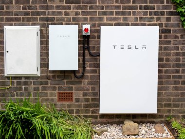 Tesla Powerwall 2 ve Yedekleme Kapısı 2 bir tuğla ev duvarına kurulmuş