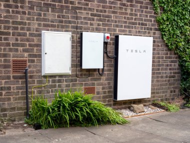 Tesla Powerwall 2 ve Yedekleme Kapısı 2 bir tuğla ev duvarına kurulmuş