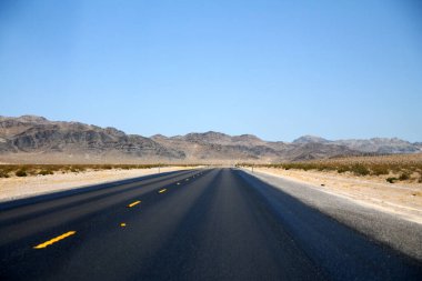 Nevada Çölü 'nün uzun sokağında, açık mavi gökyüzünün altında asfalt.