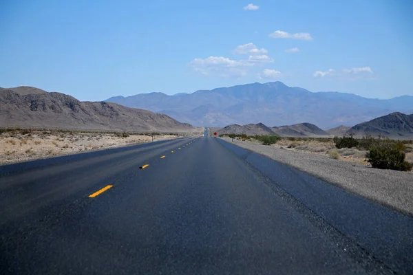 加利福尼亚沙漠中一条长长的柏油路尽头的群山 蓝蓝的天空下 — 图库照片