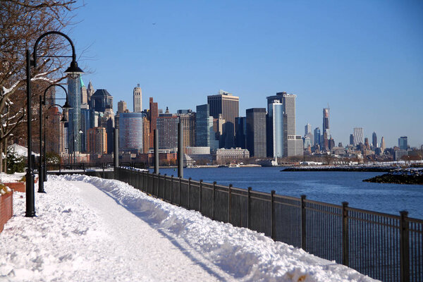 The snow path of the Hudson river walkaway with downtown Manhattan on the back from Paulus Hook in Jersey City