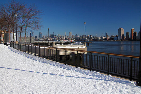 Midtown Manhattan and the Empire State Building with the snow from Hudson River Walkaway in Jersey City