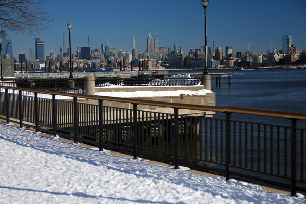 Midtown Manhattan and the Empire State Building with the snow from Hudson River Walkaway in Jersey City