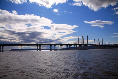 New York 'taki Hudson Nehri üzerinde bulutlu ve mavi gökyüzü olan uzun Vali Cuomo Köprüsü.