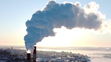 Fabrika veya elektrik santralinin bacaları güneş doğarken duman üretir. İnsansız hava aracının hava manzarası. Ekolojik hava kirliliği, çevre, iklim değişikliği, küresel ısınma, 4k video