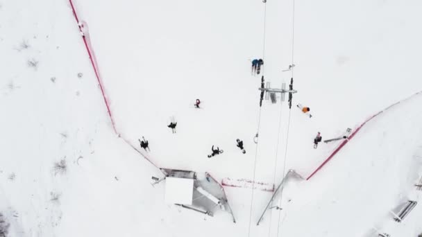 スキーリゾートのケーブルウェイでドローンからのトップビューを閉じます。スキーリフト山のリゾートで雪の冬の斜面にスキーヤーやスノーボーダーを輸送エレベーター — ストック動画
