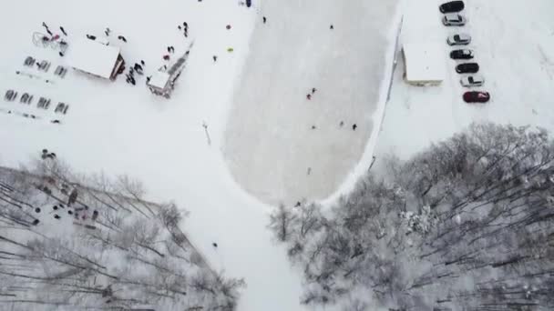 Eine winterliche Eisbahn, gefilmt von einer Drohne an einem sonnigen frostigen Tag. Kinder und Erwachsene, Hockeyspieler Schlittschuhlaufen auf dem Eis. — Stockvideo