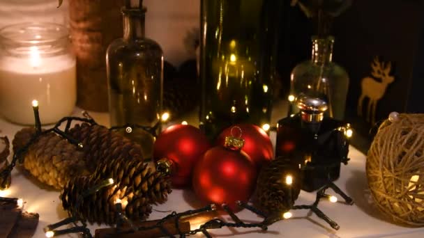 Decoraciones de Navidad, luces intermitentes, Año Nuevo 2022 4k fondo. Árbol de Navidad bolas rojas, regalo, vela, conos de abeto, botellas, ciervos — Vídeo de stock