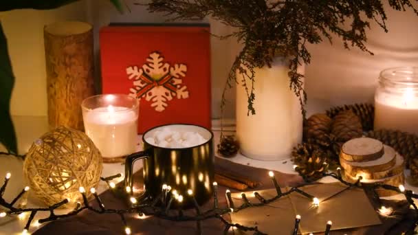 Рождественские украшения, мигающие огни, Новый 2022 год, 4k фон. Рождественский подарок, чашка кофе, красные шарики, свеча, фировые конусы, бутылки. — стоковое видео