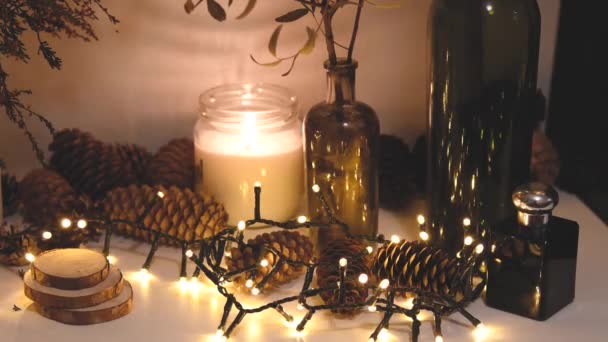 Decorações de Natal, luzes piscando, Ano Novo 2022, fundo 4k. Vela de Natal, cones de abeto, garrafas — Vídeo de Stock
