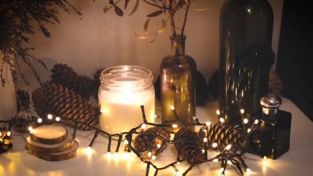 Décorations de Noël, lumières clignotantes, Nouvel An 2022, fond 4k. Bougie de Noël, cônes de sapin, bouteilles — Video