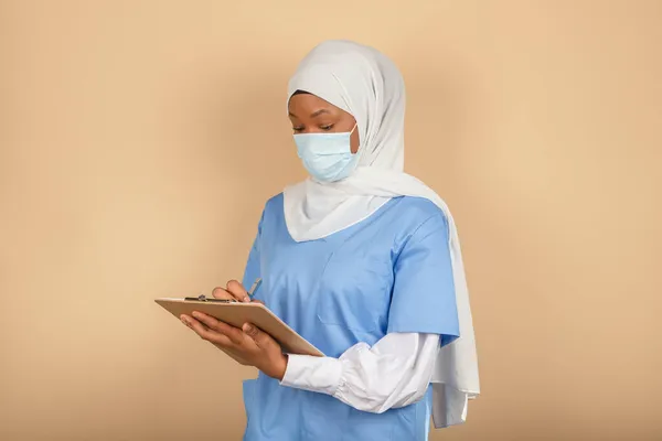 Mladá Muslimská Sestra Stojící Chirurgické Masce Všimne Podložce Žluté Stěně — Stock fotografie