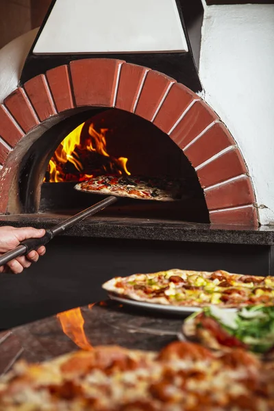 Şef pizzayı alır. İtalyan pizzası odun ateşinde pişirilir.