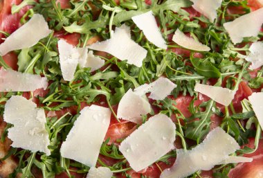 Pizza arkaplanı - jambon, roka ve parmesanlı pizzanın makro fotoğrafı.