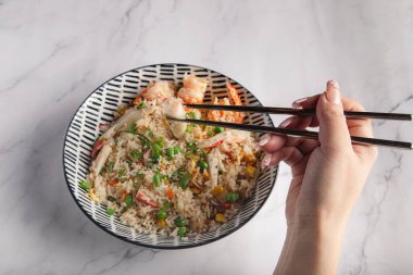 Kadın eli yemek çubuğuyla yakın plan Asya yemeği yiyor..