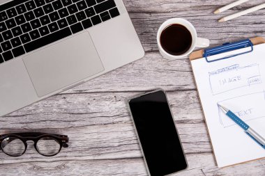 Bilgisayar ve ahşap bir masanın üstünde akıllı bir telefon olan site tasarımcısı çalışma masası.