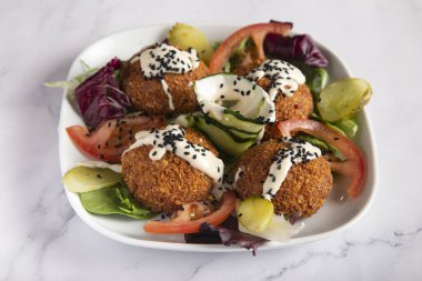 Sebzeli taze falafel ve mermer masada beyaz tabakta tzatziki sosu. 