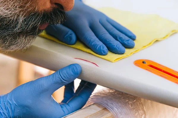 Surfer repairing a blow to a surfboard.