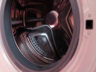Close Up Of Men Loading Dirty Clothes Into Washing Machine
