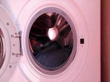 Men's hands load clothes, wardrobe into the washing machine, washing it at home. Daily life, housework.