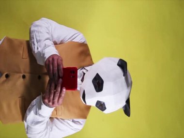 Panda maskeli üzgün adam cep telefonundan kötü haberler alıyor. Dikey biçimdeki video