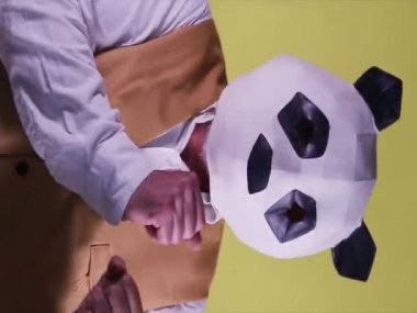 Sarı arka planda dans eden panda maskeli bir adam. portre biçimi