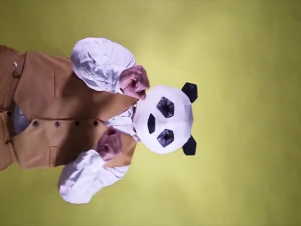 黄色の背景にパンダの頭のマスクを持つ愚かな男のダンスとお祝い 垂直形式のビデオ — ストック動画