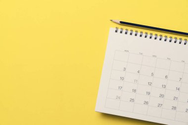 sarı masa arkaplanındaki takvim ve kalemi kapat, iş toplantısı ya da seyahat planlama konseptini planla