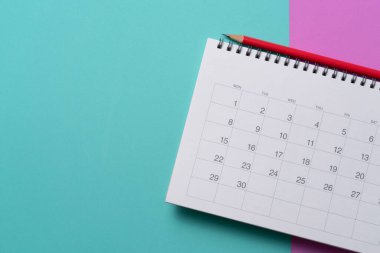 Yeşil ve pembe masa arkaplanındaki takvim ve kalemi kapat, iş toplantısı ya da seyahat planlama konseptini planla