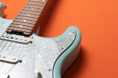Electric guitar on orange table background, close up