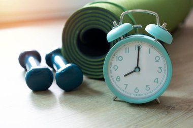Spor aletleri, dambıl, yeşil yoga minderli çalar saat