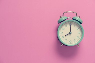 Pembe masa arkaplanındaki yeşil alarm saati, antika tarzı