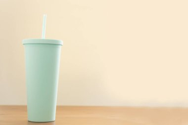 Yeşil fincanı ya da cam plastiği kapat ve ahşap masaya saman koy. içki veya içecek konsepti