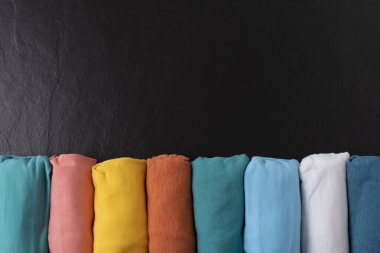 Siyah masa arkaplanındaki renkli t-shirtlerin kapağı, seyahat kavramı