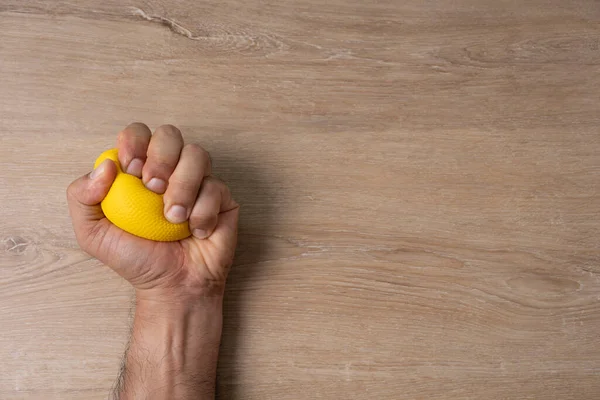 Χέρια Ενός Άντρα Που Πιέζει Μια Κίτρινη Μπάλα Άγχους — Φωτογραφία Αρχείου